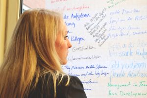 Eine Frau steht vor einem Whiteboard und liest die Notizen