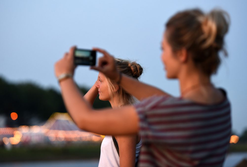 Zwei Frauen stehen an der anderen Weserseite und machen ein Foto von der Breminale