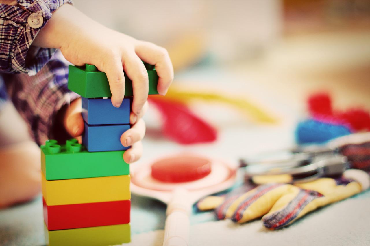 Eine Kinderhand stapelt bunte Bauklötze aufeinander